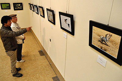 来場者に写真の説明をする与名正三さん（左）＝2016年3月29日、生駒市西松ケ丘の市芸術会館「美楽来」