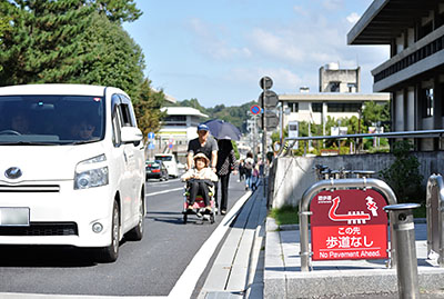 歩道が撤去され車道になった道路の端を通行する車いすの人