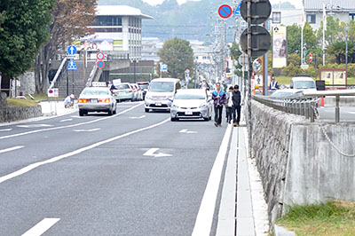 歩行者をよけて通過しようとする車の後方から隣接車線の車が迫る＝2016年11月6日午前9時36分ごろ