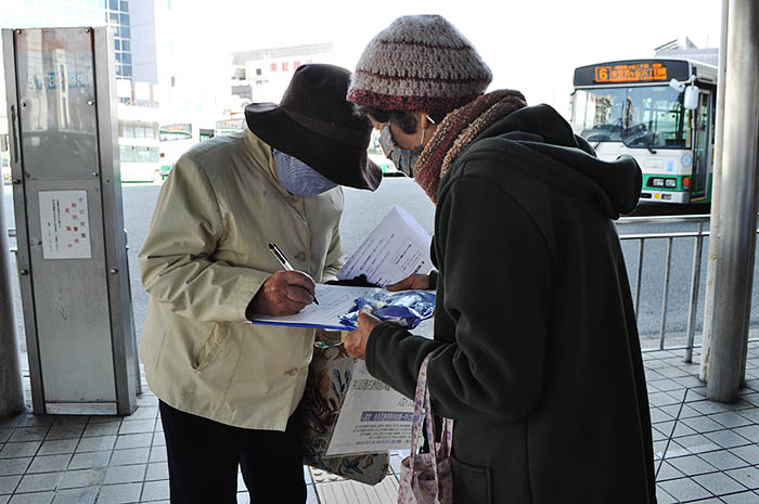 「西奈良県民センター跡地利用を考える会」会員の呼び掛けに応じて署名する人＝2020年12月18日、奈良市学園南3丁目の近鉄学園前駅前