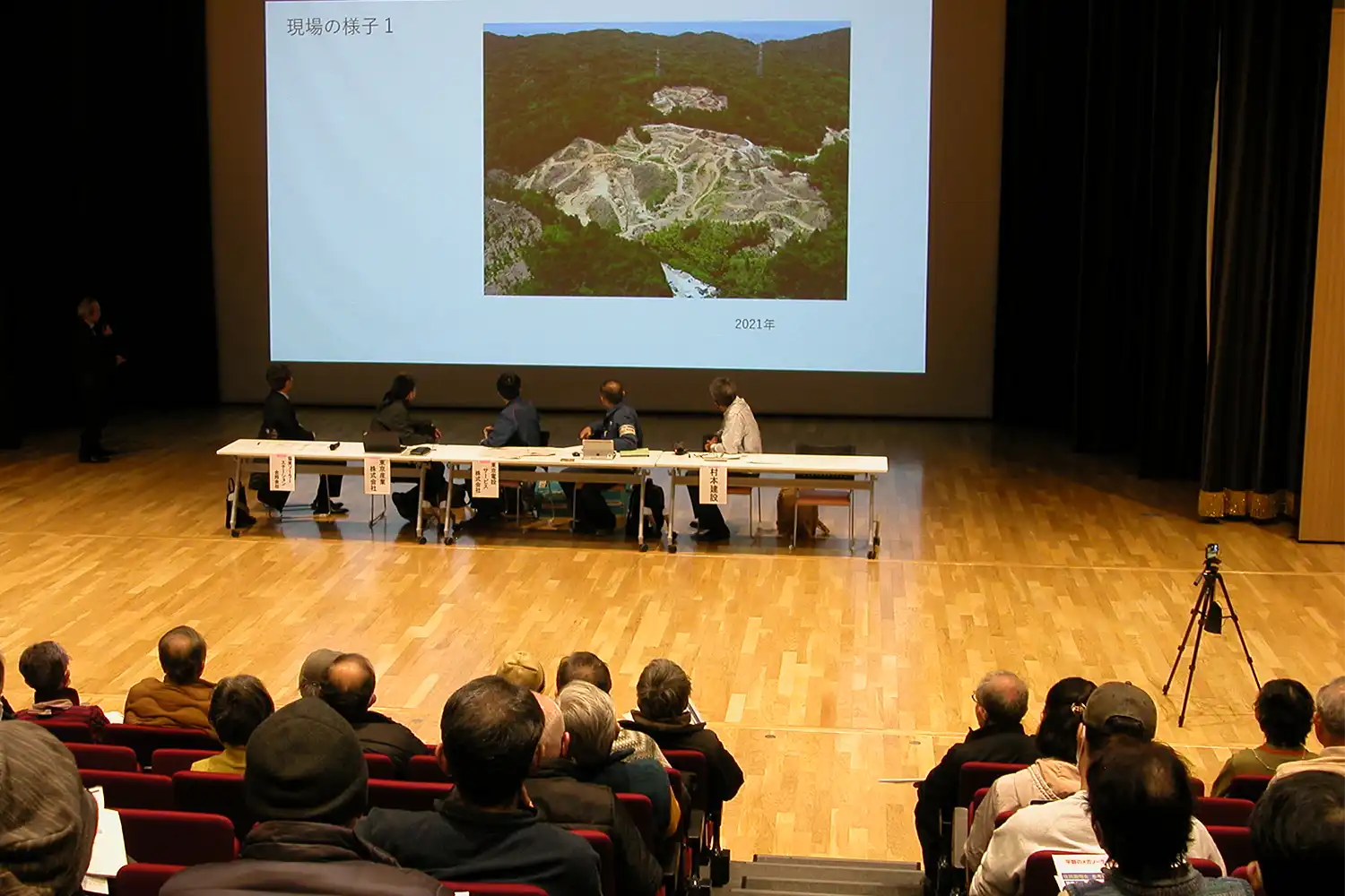 山林が伐採された現場の画像を示しながら計画への疑問を述べる住民（左奥）＝2024年3月9日、平群町吉新3丁目の町総合文化センター