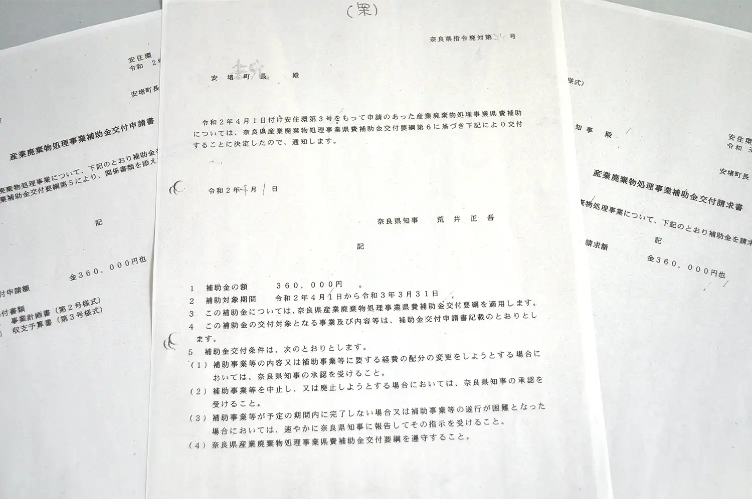 安堵町に対する県産業廃棄物処理事業県費補助金の交付決定通知書（中央）。左は町の交付申請書、右は交付決定を受けた町の請求書＝住民訴訟原告の池田さん提供