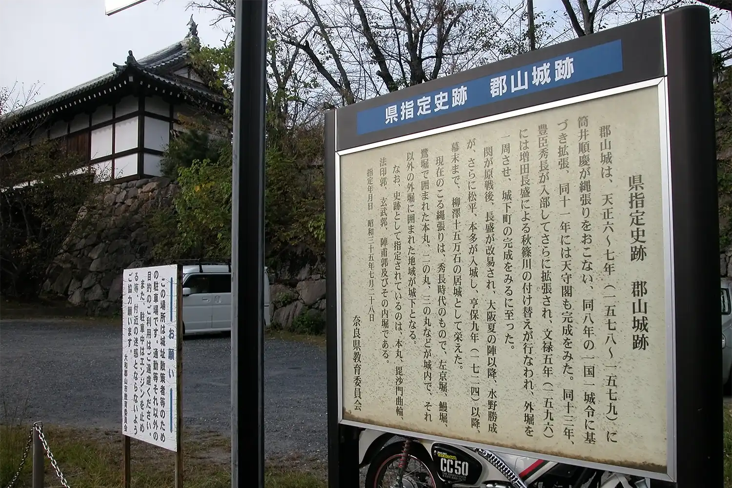 国史跡に指定された後、2年間、表示が「県指定史跡」のままになっている郡山城跡入り口の案内板＝2024年10月25日、奈良県大和郡山市、浅野詠子撮影